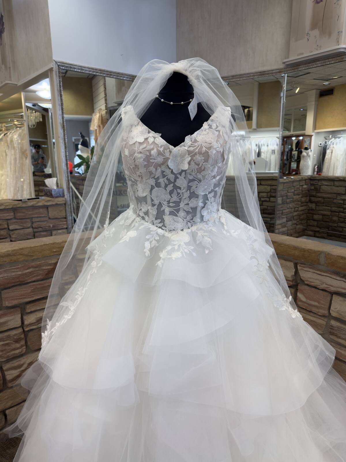 Tiered ball gown with a lace bodice and a tulle veil on a dress form