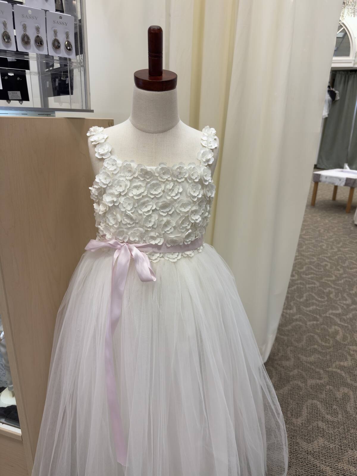 Flower girl dress with a rosette bodice, pink sash, and tulle skirt