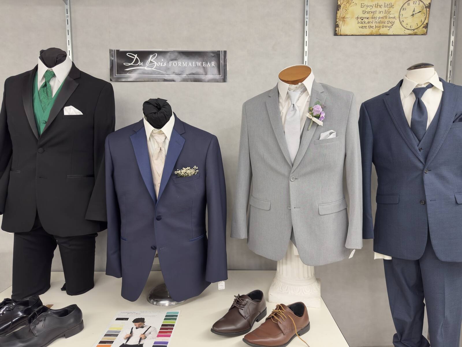 A black tuxedo and three DuBois suits in navy, light gray, and blue, with dress shoes