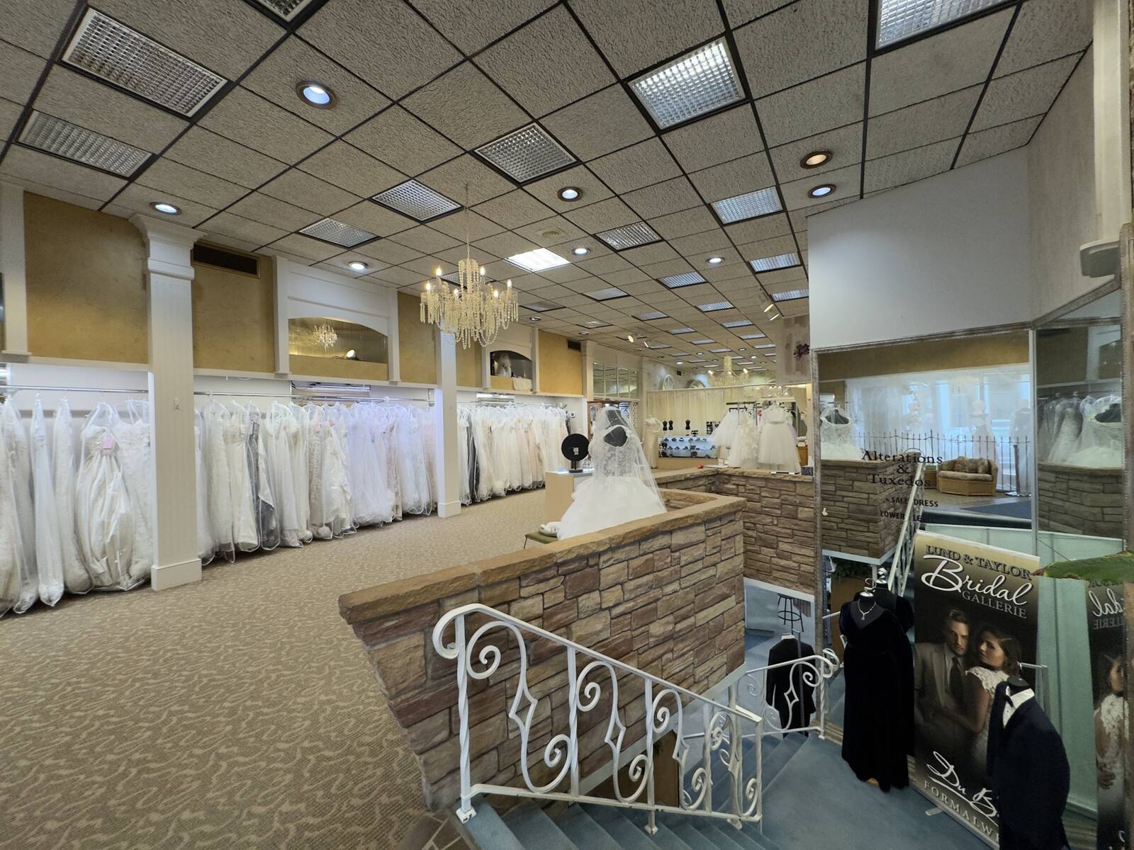 The two-story Lund & Taylor showroom seen from the upstairs balcony, with racks of wedding gowns below a chandelier